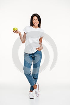 Full length portrait of a smiling woman holding green apple