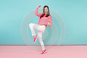 Full length portrait of smiling young woman in knitted rose sweater, white pants posing isolated on bright pink blue