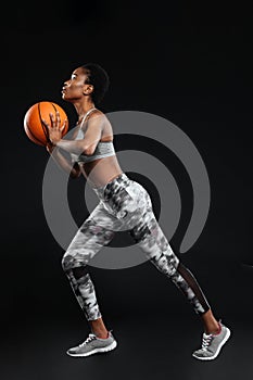 Full length portrait of a sports woman holding basketball ball