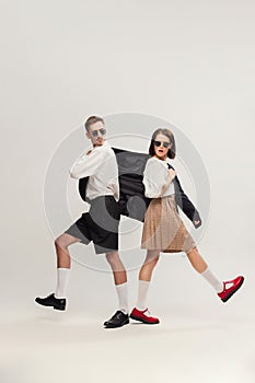 Full-length portrait of stylish young couple, man and woman in retro suit posing  over grey studio background
