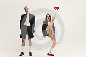 Full-length portrait of stylish young couple, man and woman in retro suit posing  over grey studio background