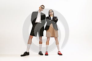 Full-length portrait of stylish young couple, man and woman in retro suit posing  over grey studio background