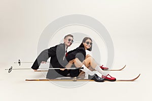 Full-length portrait of stylish young couple, man and woman in retro suit posing  over grey studio background