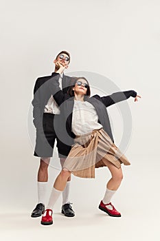 Full-length portrait of stylish young couple, man and woman in retro suit posing  over grey studio background