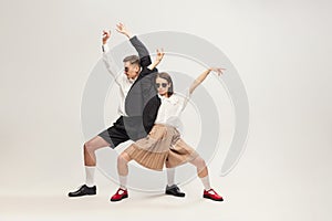 Full-length portrait of stylish young couple, man and woman in retro suit posing  over grey studio background