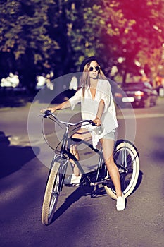 Full length portrait of stylish young woman on a bike