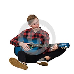 Full length portrait of talented boy teenager playing on the acoustic guitar seated on the floor isolated over white background.