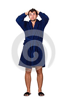 Full length portrait of tardy young man wears blue bathrobe holding hands to head, unable to wake up in time to get to work,