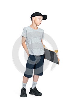 Full-length portrait of a teenager in a T-shirt, shorts and a cap, holding a skateboard in his hand, isolated