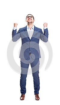 Full length portrait thankful and pleased businessman keeps fists raised up, looking contented upwards isolated on white