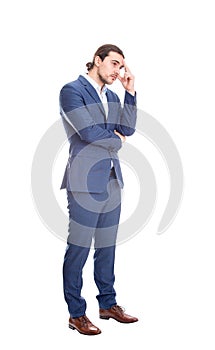 Full length portrait of thoughtful and melancholic businessman keeps hand to head, looks pensive isolated on white background.