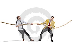 Full-length portrait of two motivated and concentrated employees doing tug of war isolated over white background