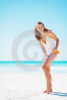 Full length portrait of woman applying sun screen creme