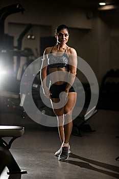 Full length portrait of woman bodybuilder standing on tiptoes and demonstrated her athletic body