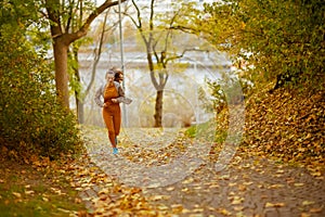 Full length portrait of woman in fitness clothes in park jogging