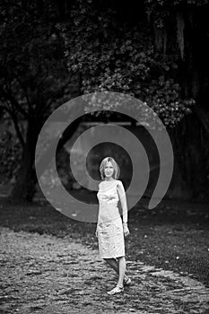 Full-length portrait of a woman standing on a path in a park. Black and white photo.