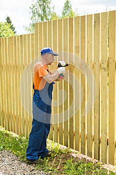 Full-length portrait of worker constructing wooden fence