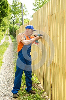 Full-length portrait of worker constructing wooden fence