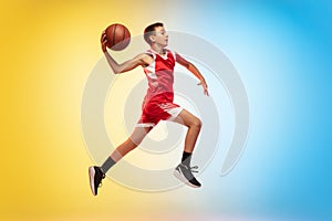 Full length portrait of a young basketball player with ball on gradient background