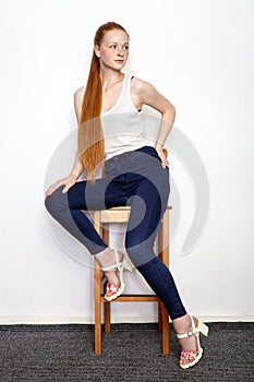 Full length portrait of young beautiful redhead beginner model woman in white t-shirt blue jeans practicing posing showing emotion