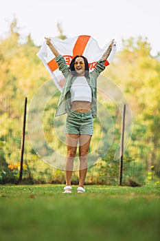 Full-length portrait of young beautiful smiling girl holding flag of England