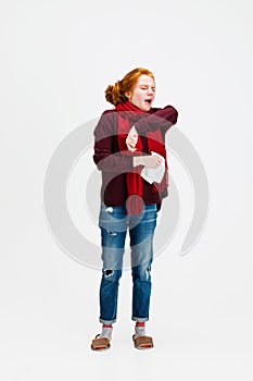 Full-length portrait of young Caucasian girl feeling sick, sneezing isolated over white background. Flu, cold, allergy