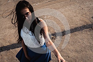 Portrait of young fashionable brunette woman practicing model posing outdoors against urban style background of grey concrete wall