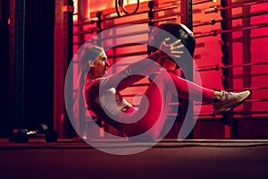 Full-length portrait of young fit girl training, doing sit up with ball isolated over gym background