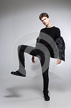 Full length portrait of young fit man in dark cloths on the white background. Young Male Fashion Model Posing In Casual Outfit.