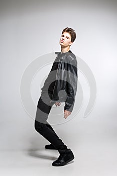Full length portrait of young fit man in dark cloths on the white background. Young Male Fashion Model Posing In Casual Outfit.