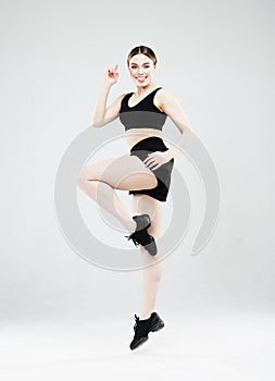 Full length portrait of a young fitness woman in sportswear posing and jumping isolated over gray background