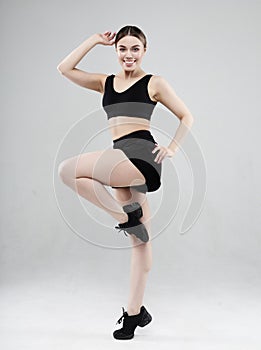 Full length portrait of a young fitness woman in sportswear posing and jumping isolated over gray background