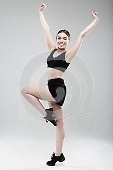 Full length portrait of a young fitness woman in sportswear posing and jumping isolated over gray background