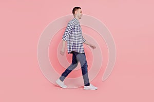 Full length portrait of young handsome guy go walk step happy positive smile isolated over pink background
