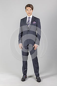 Full length portrait on young handsome man. Elegant businessman in suit isolated on a grey background.