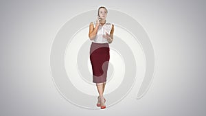 Young happy woman standing and talking on the phone on gradient background.