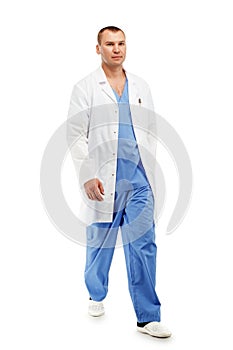 Full length portrait of a young male doctor in a medical surgical blue uniform in motion leaving the operating room