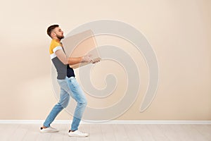 Full length portrait of young man carrying carton box