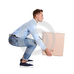 Full length portrait of young man lifting heavy cardboard box on white background