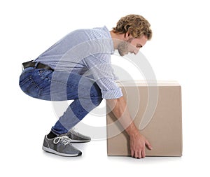 Full length portrait of young man lifting heavy cardboard box on white background.