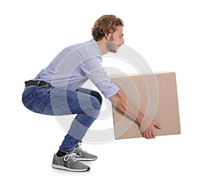 Full length portrait of young man lifting heavy cardboard box on white background