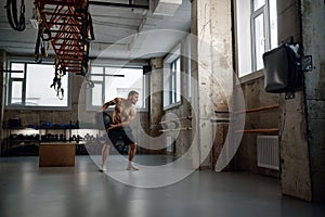 Full length portrait of young muscular man training with med ball in gym