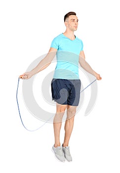 Full length portrait of young sportive man training with jump rope on white