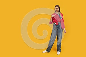 Full-length, portrait of young woman with flag of South Africa in hands. Orange background. Study and travel in South Africa