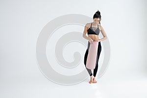 Full length portrait of a young woman holding yoga mat isolated