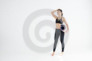 Full length portrait of a young woman holding yoga mat isolated