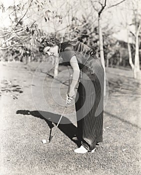 Full length portrait of young woman playing golf on field