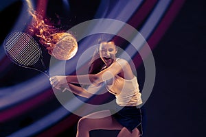 Full length portrait of young woman playing tennis on dark studio background