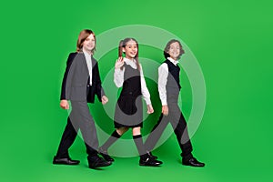 Full length profile photo of funky small girl boys go wave wear school uniform isolated on green background