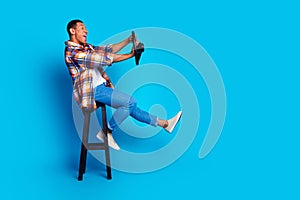 Full length profile photo of nice young man beep wheel empty space wear shirt  on blue color background photo